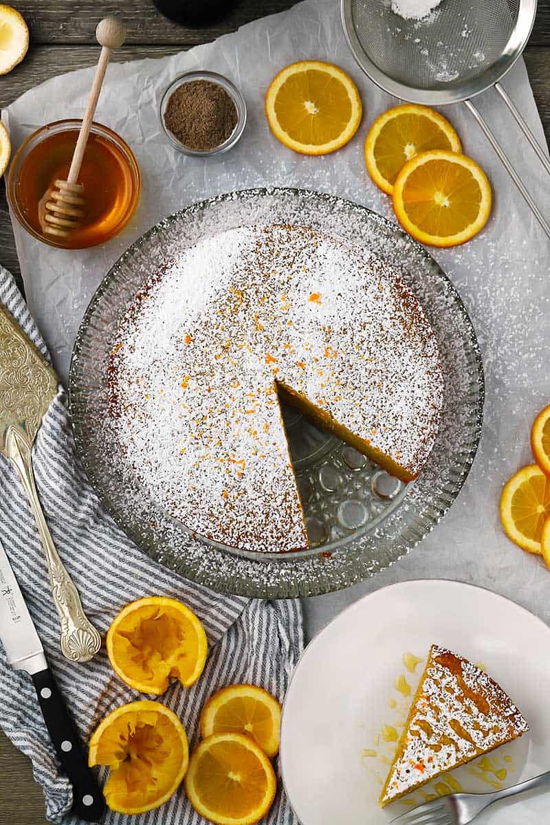 Overhead photo of an olive oil cake with oranges around it.