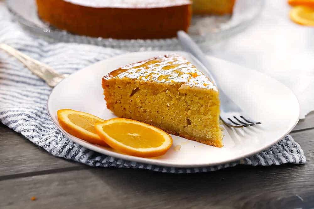A slice of cake with orange slices and a fork on a plate.