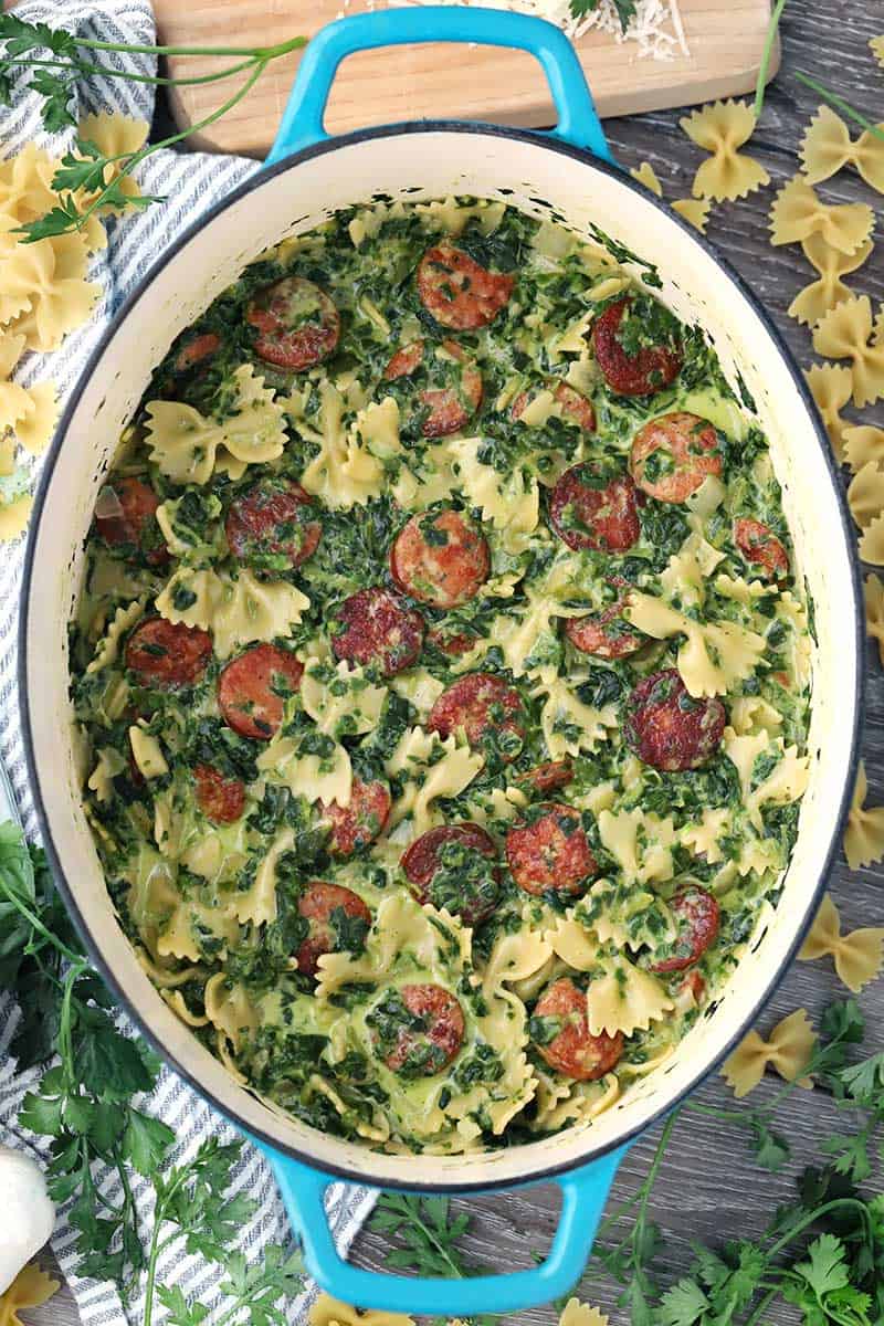 A Dutch Oven with sausage spinach pasta inside.