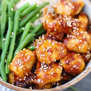 Close up photo of a bowl of sesame chicken garnished with sesame seeds.