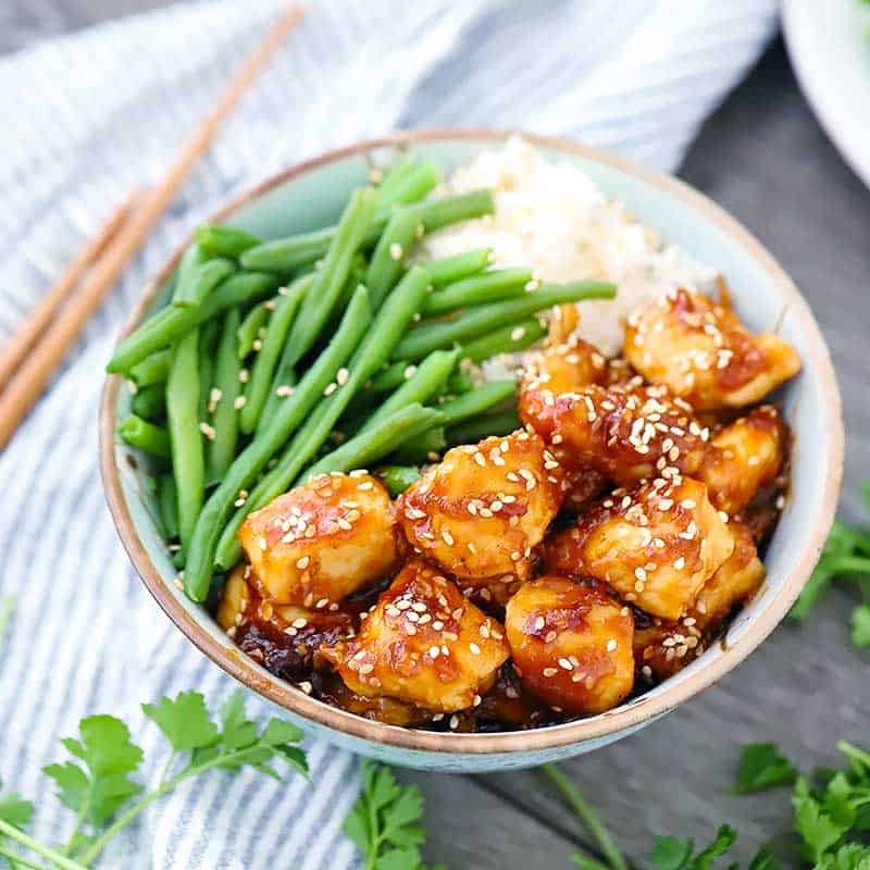 Square photo of sesame chicken in a bowl.