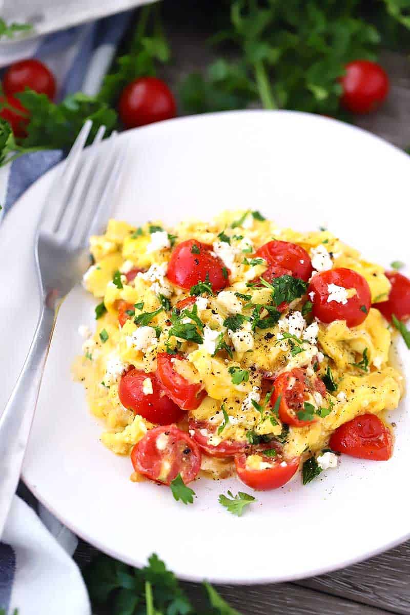 Close up photo of scrambled eggs with feta and tomatoes.