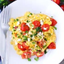 Overhead photo of a plate of olive oil scrambled eggs with feta and tomatoes.