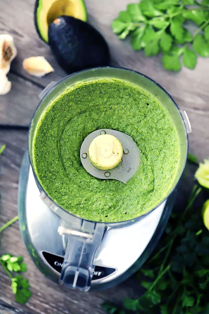 Food processor with avocado sauce in it.