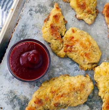 Chicken tenders on a baking sheet with ketchup.