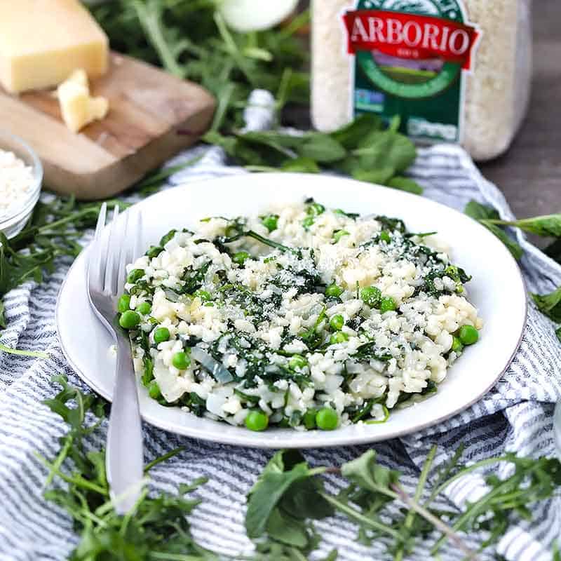 A plate of risotto with a jar of arborio rice in the background