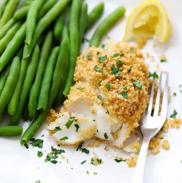 A plate of baked haddock with breadcrumb topping and green beans