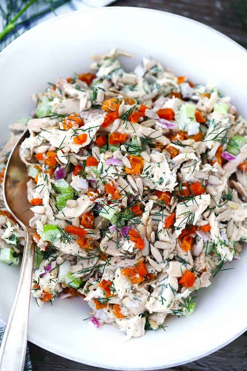 Apricot Chicken Salad with Dill and Sunflower Seeds in a bowl with a spoon.
