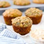 Three zucchini muffins with a pan behind them