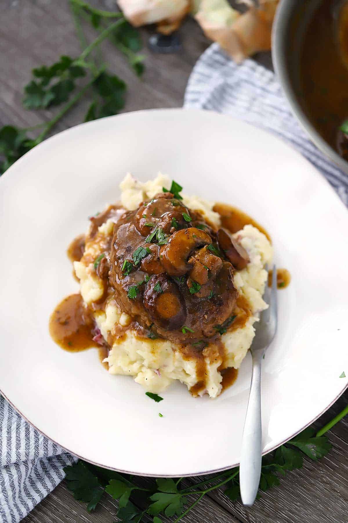 A plate with salisbury steak, mashed potatoes, and mushroom gravy.