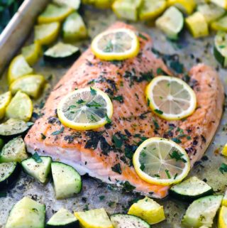 garlic butter sheet pan salmon with veggies with lemon slices on top
