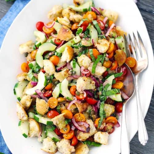 A platter of panzanella, or Italian Bread Salad, with a fork and spoon.