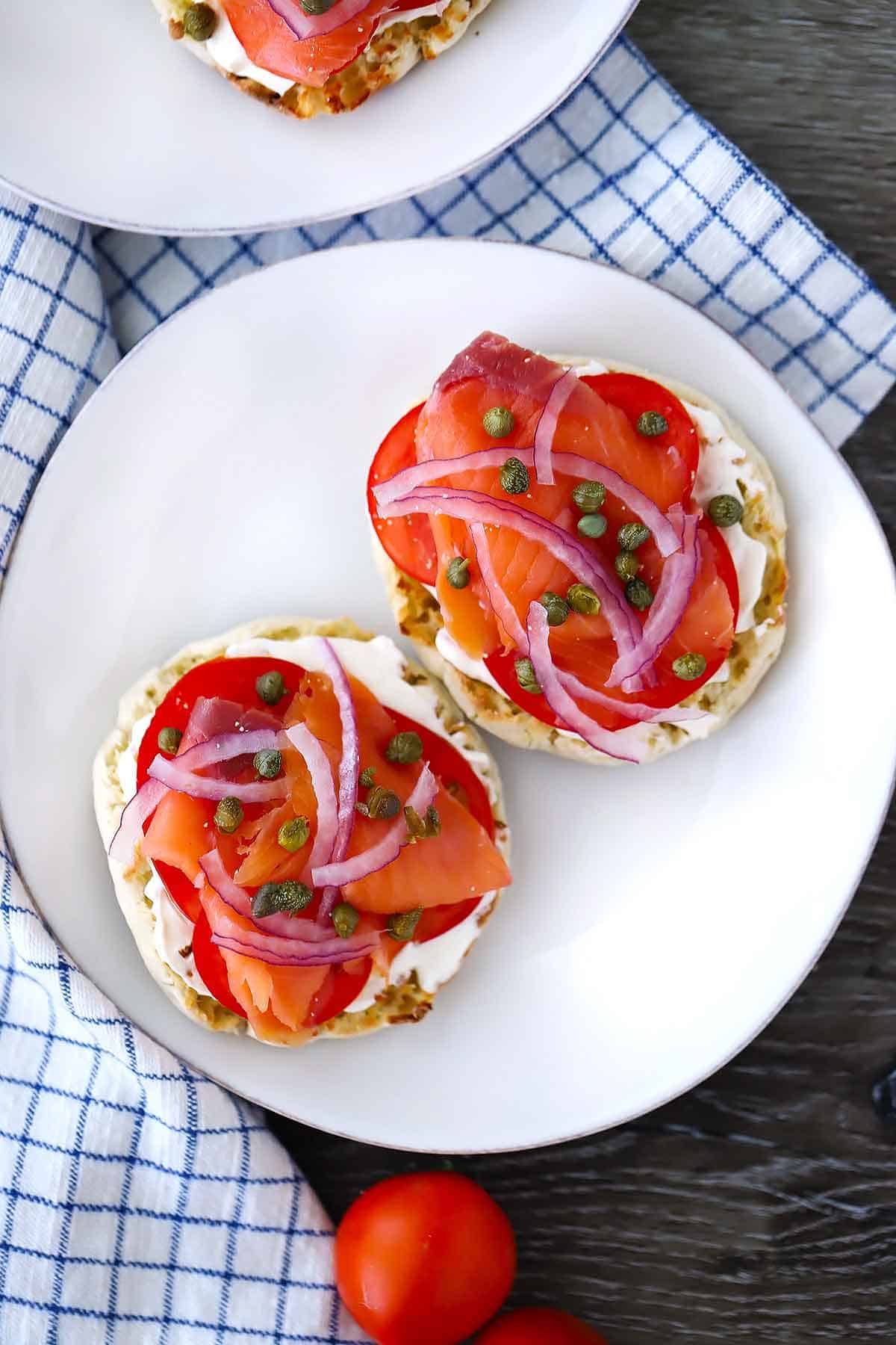 Overhead photo of a smoked salmon english muffin with cream cheese, capers, tomatoes, and red onion