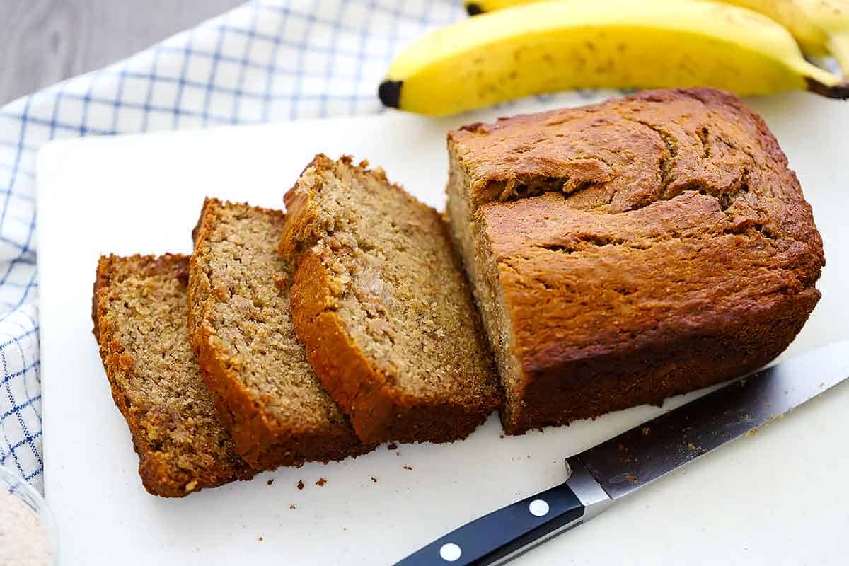 A loaf of banana bread on a cutting board sliced.