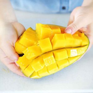 Square image of a mango diced in the peel.
