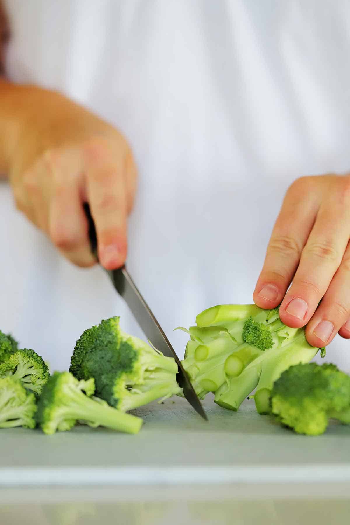 Cutting the center floret off a head of broccoli.