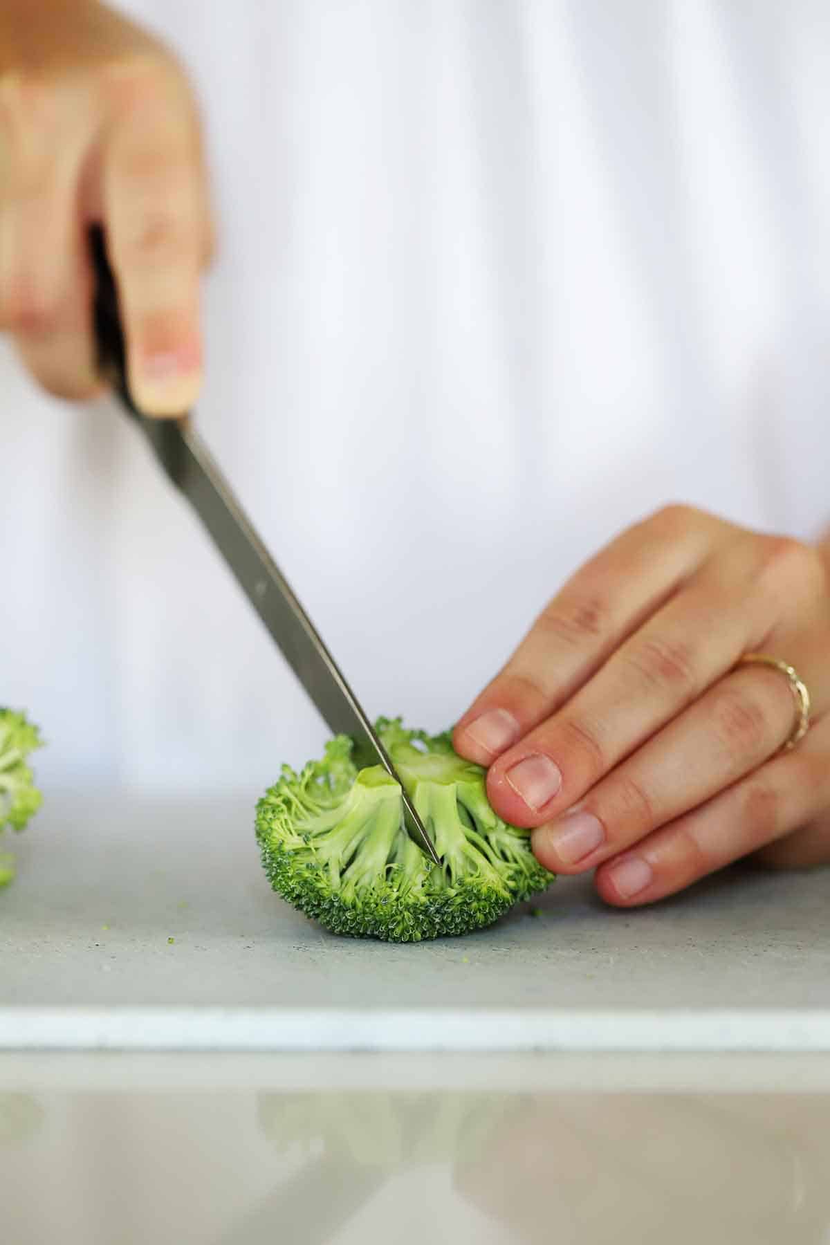 Slicing a small floret of broccoli into two pieces.