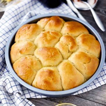 A round pan with pull-apart dinner rolls in it.