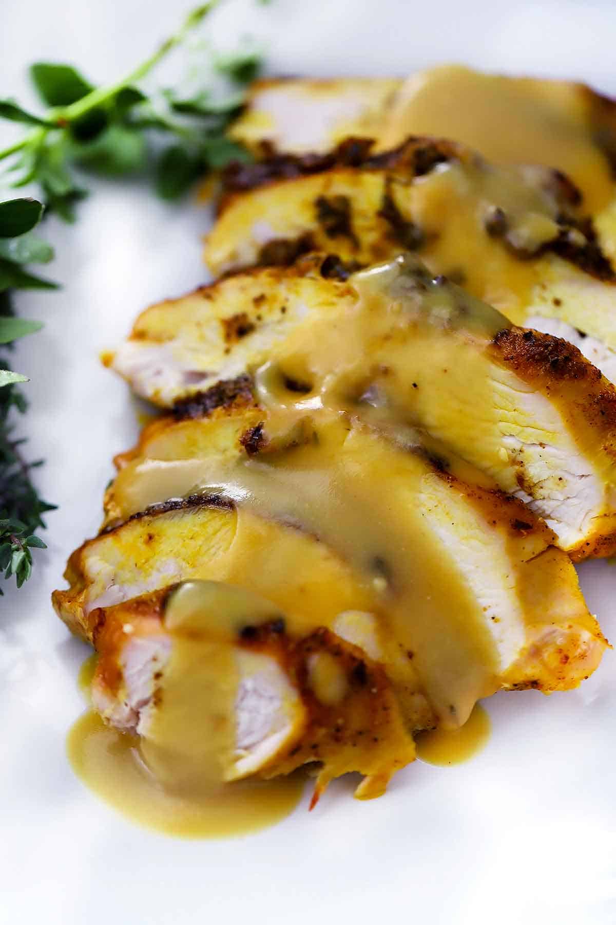 Sliced turkey breast on a white plate with gravy on top.