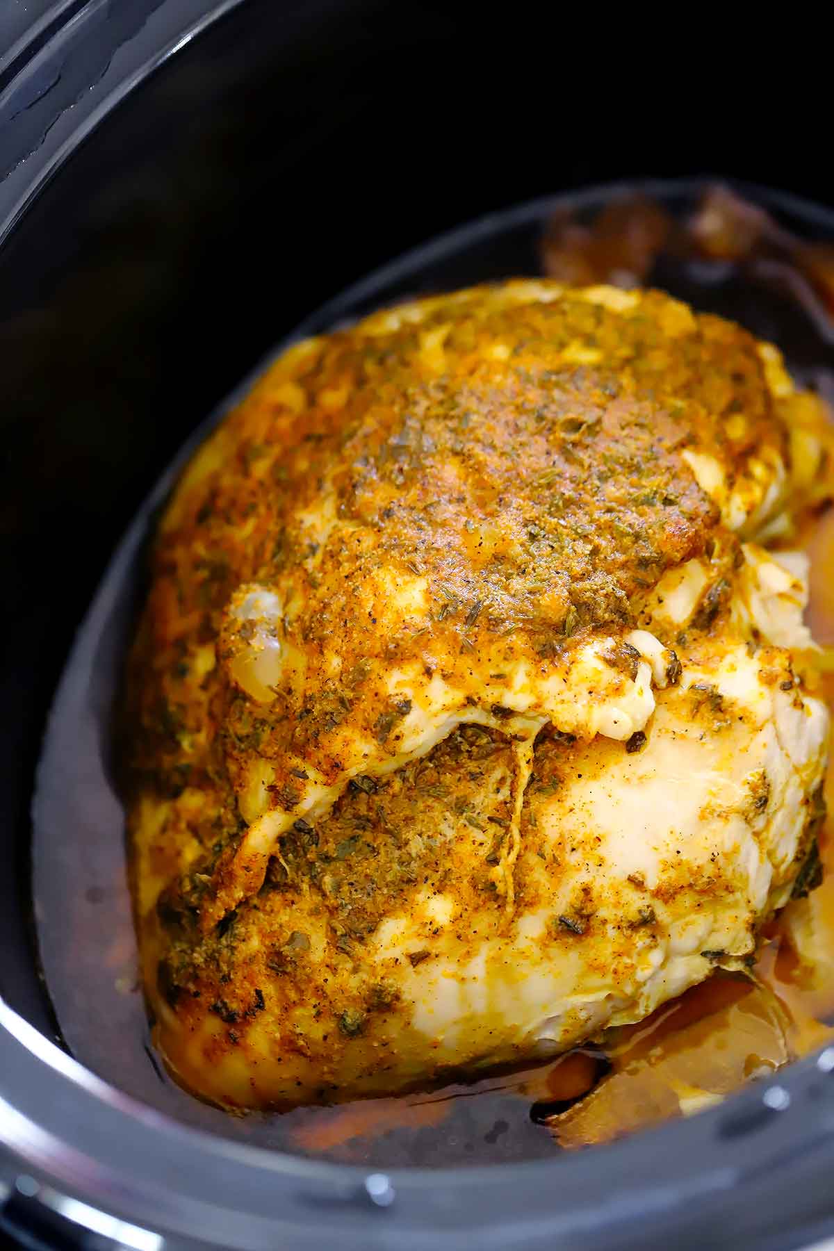 A whole boneless turkey breast in a slow cooker.