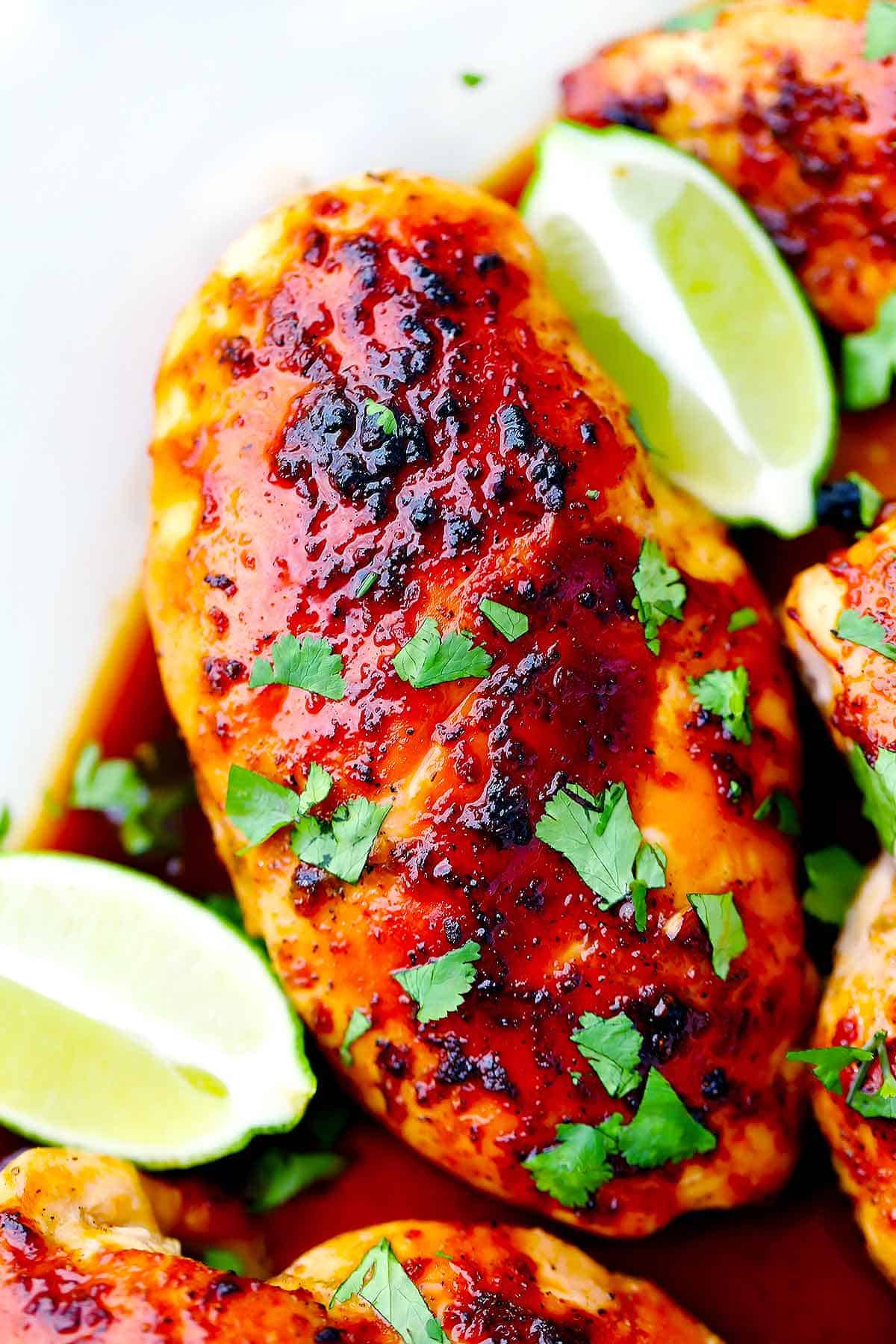 Close up photo of honey soy chicken breast with lime wedges.