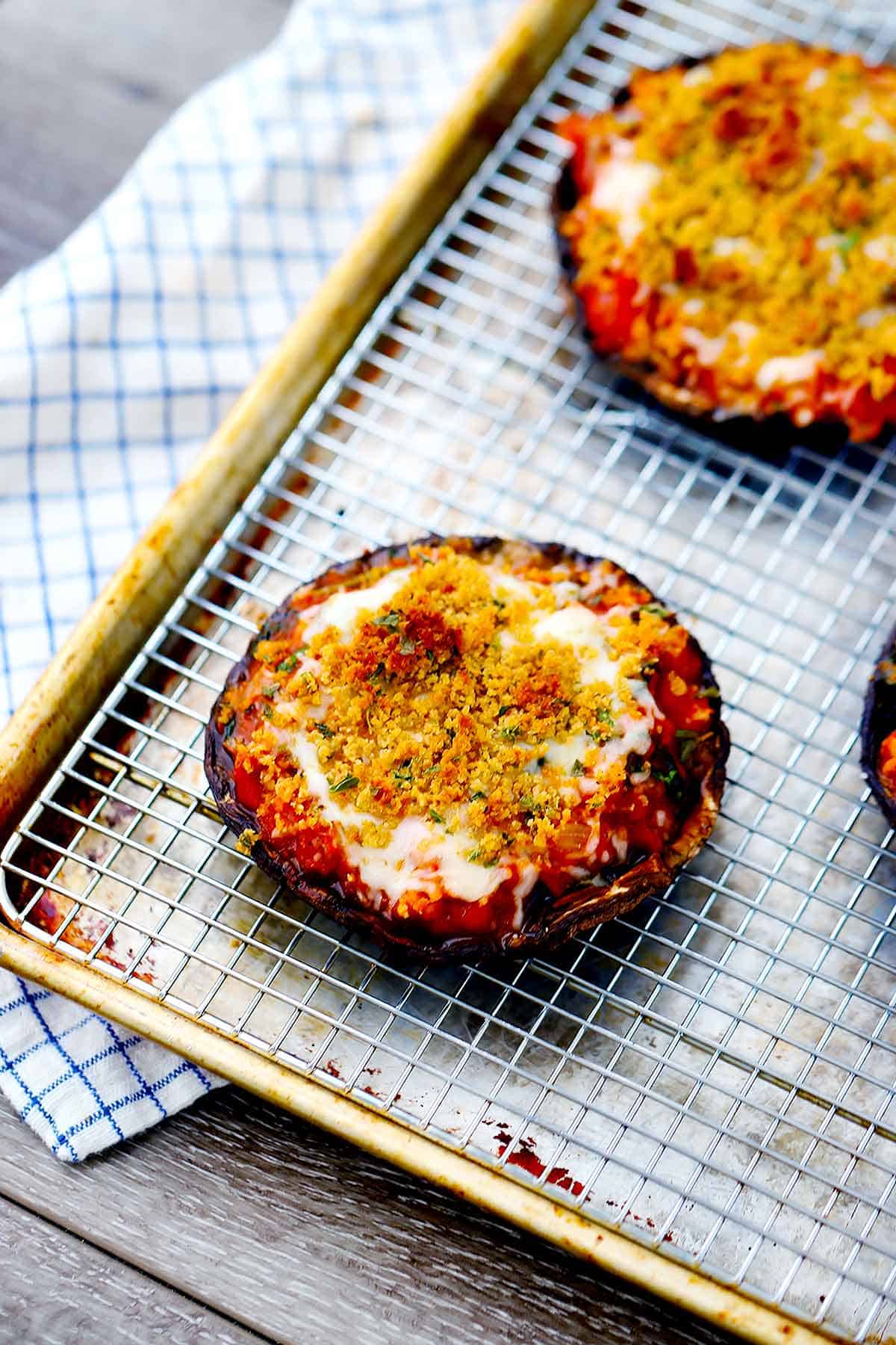 A baking sheet with a rack with stuffed portobello mushrooms on top.