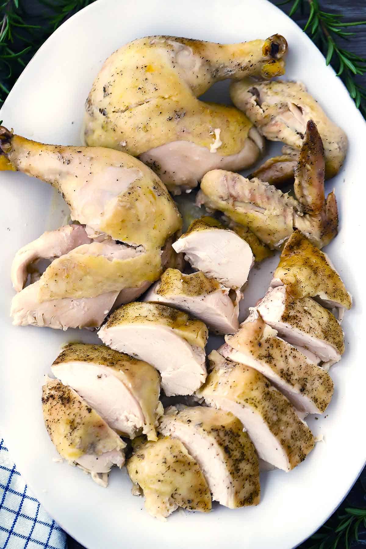 A platter of a cooked cut up and carved whole chicken