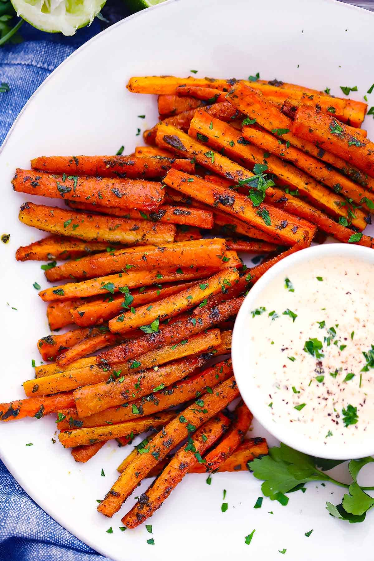 Overhead photo of carrot fries with spicy mayo dipping sauce on a white plate.