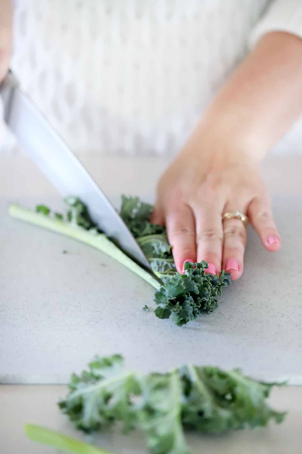 Cutting the stem off curly kale with a knife.