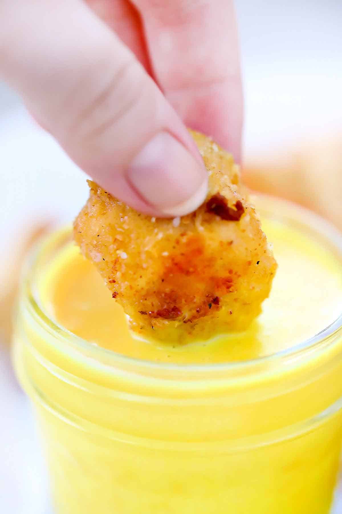 Dipping a chicken nugget into homemade honey mustard sauce.
