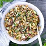 Mediterranean chickpea salad in a white bowl with a spoon in the bowl.