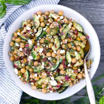 Mediterranean chickpea salad in a white bowl with a spoon in the bowl.