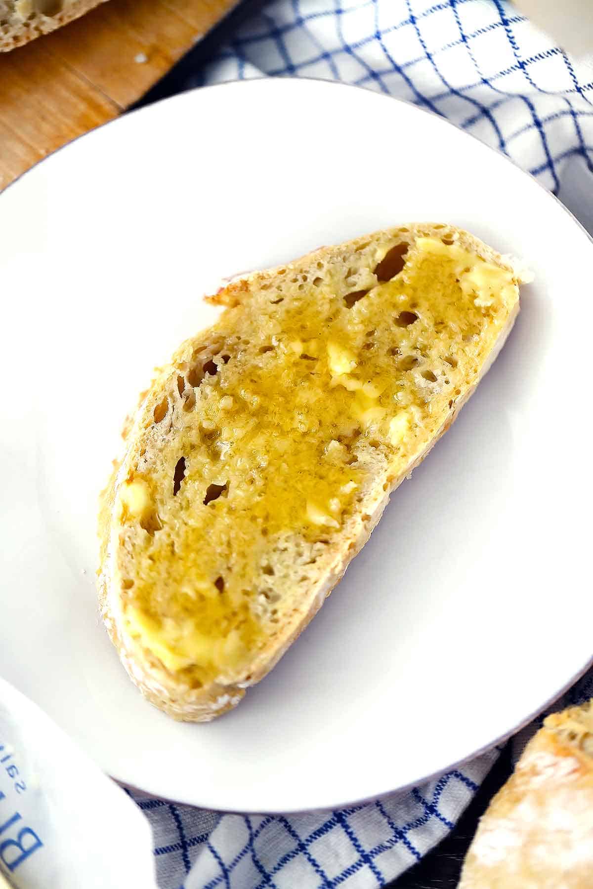 Homemade bread with salted butter and honey on a white plate.