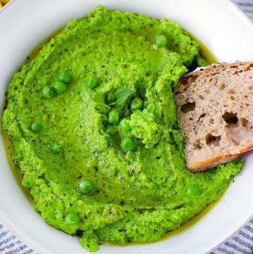 Square photo of bread being dipped in pea puree.