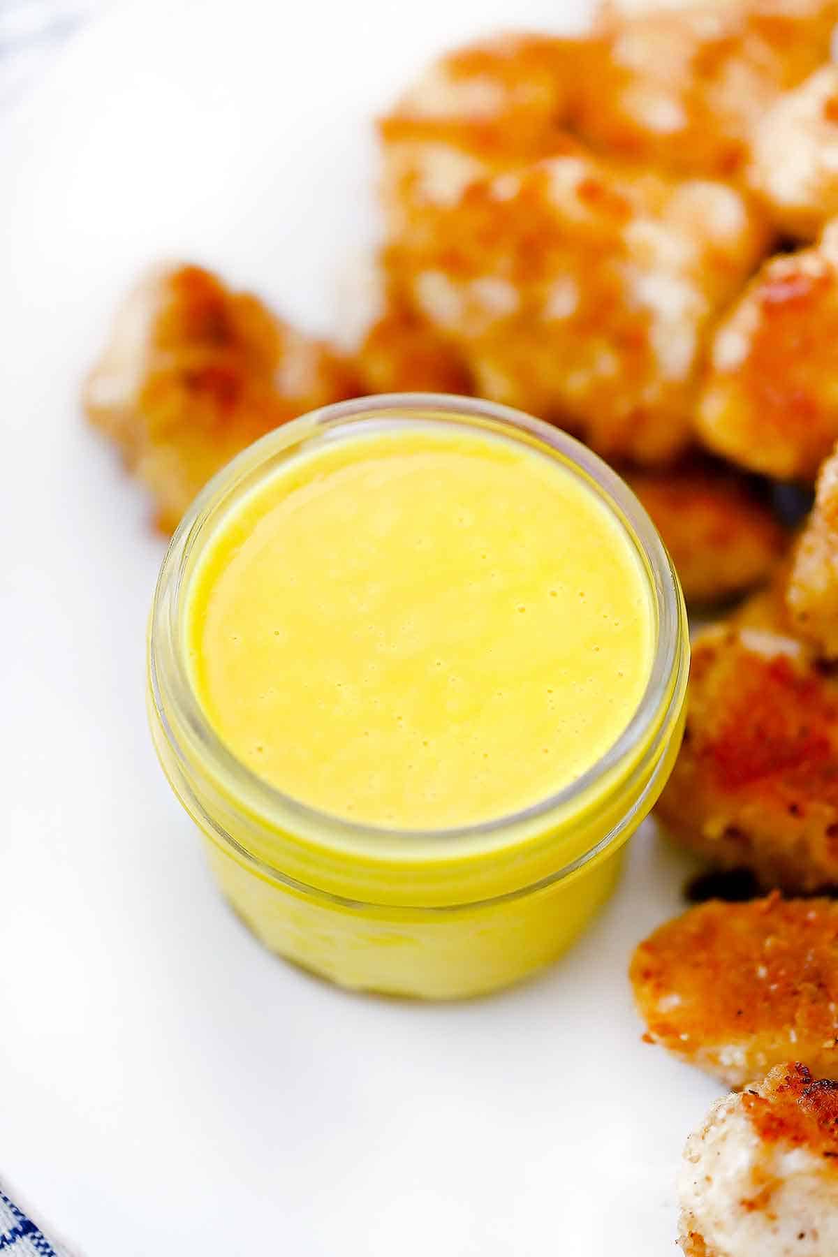 Homemade honey mustard sauce on a plate with chicken nuggets.