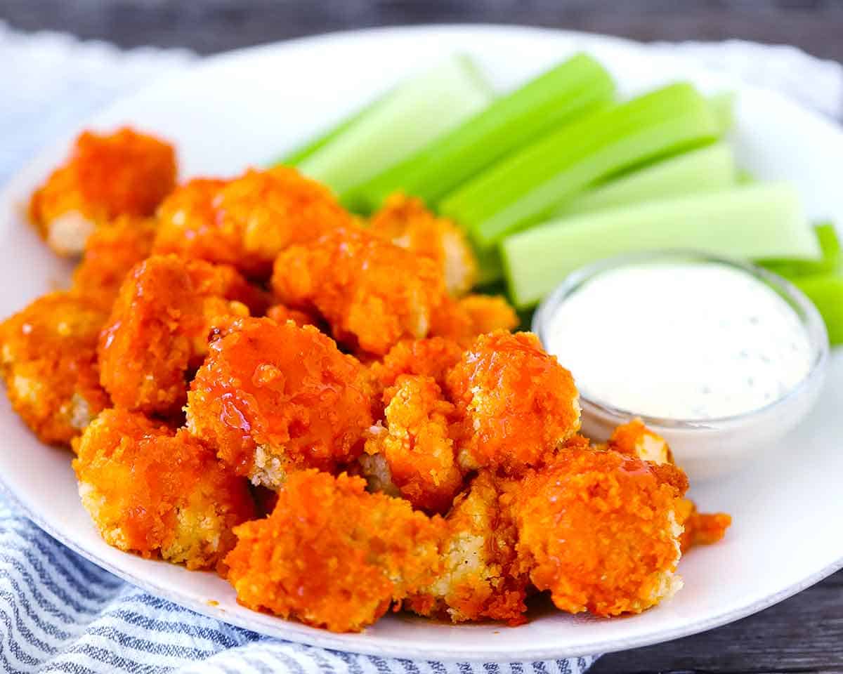 Horizontal image of buffalo cauliflower on a white plate with ranch and celery.