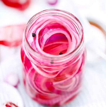 Square photo of pickled red onions in a jar.