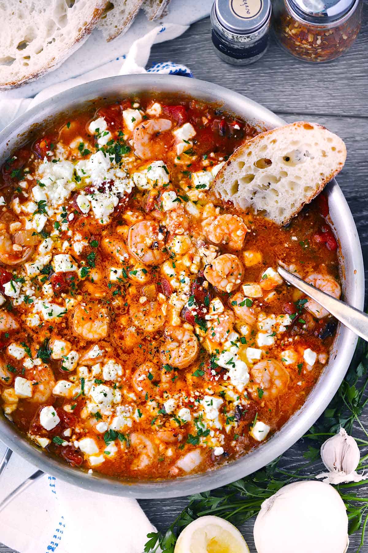 Garides saganaki, or Greek shrimp with feta and tomatoes, in a skillet with sourdough bread.