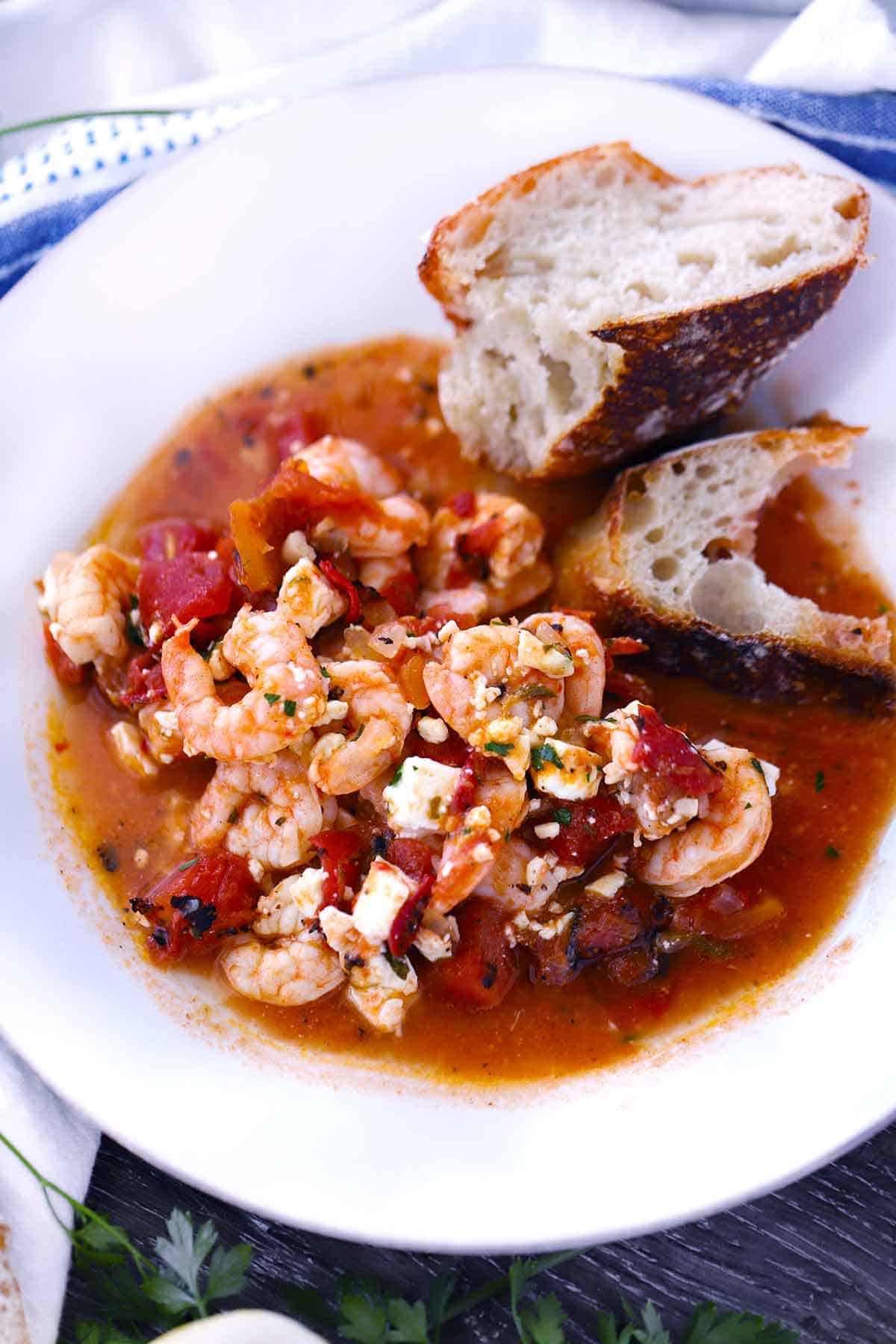 Greek shrimp with feta and tomatoes on a plate with sourdough.