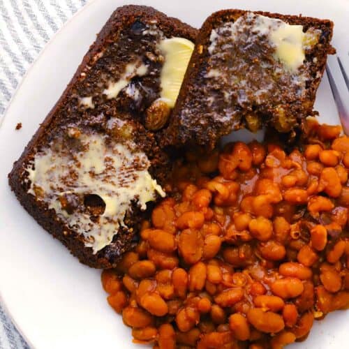 Square photo of two slices of Boston brown bread and beans on a plate.