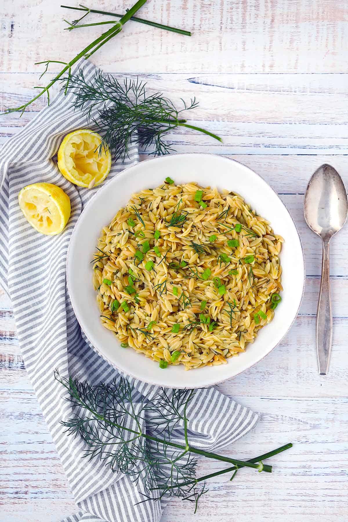 Flatlay photo of orzo pilaf with lemon and dill on the side.