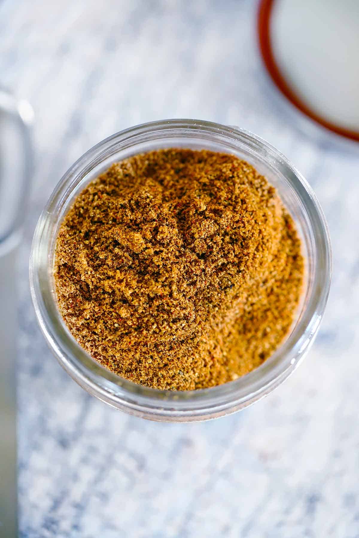 Overhead photo of a small mason jar filled with Ras el Hanout, a Moroccan spice blend.