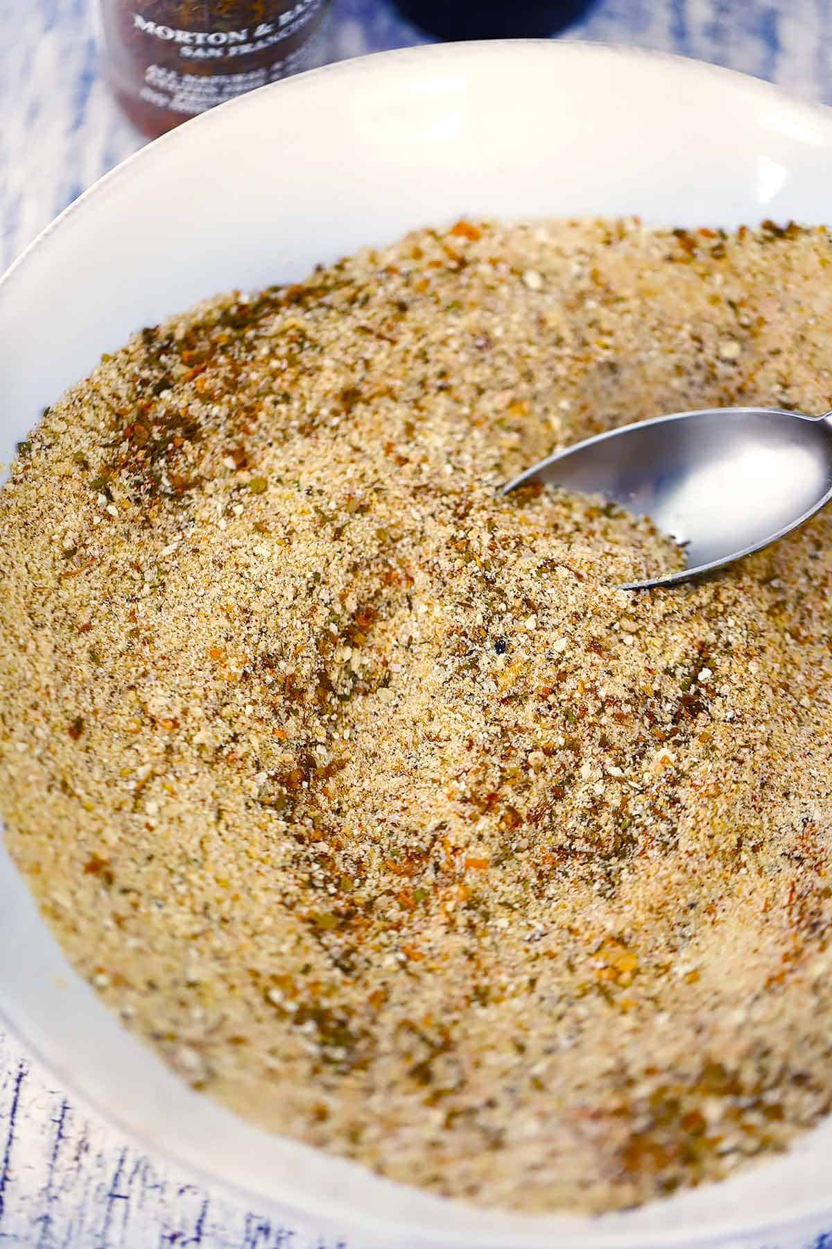 A close up photo of Italian Seasoned Bread Crumbs mixed together with a spoon.