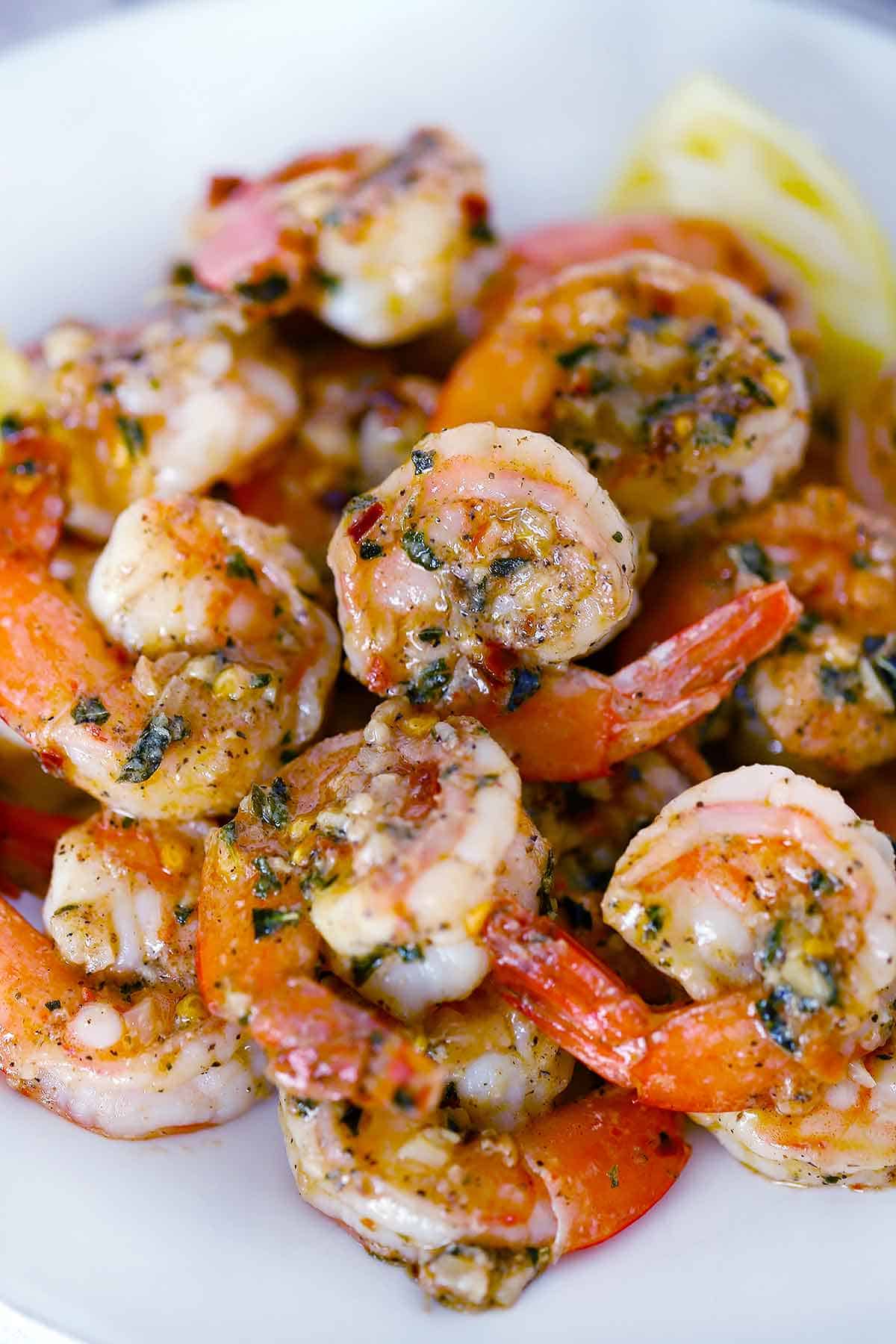 Sauteed shrimp with garlic and lemon on a white plate.