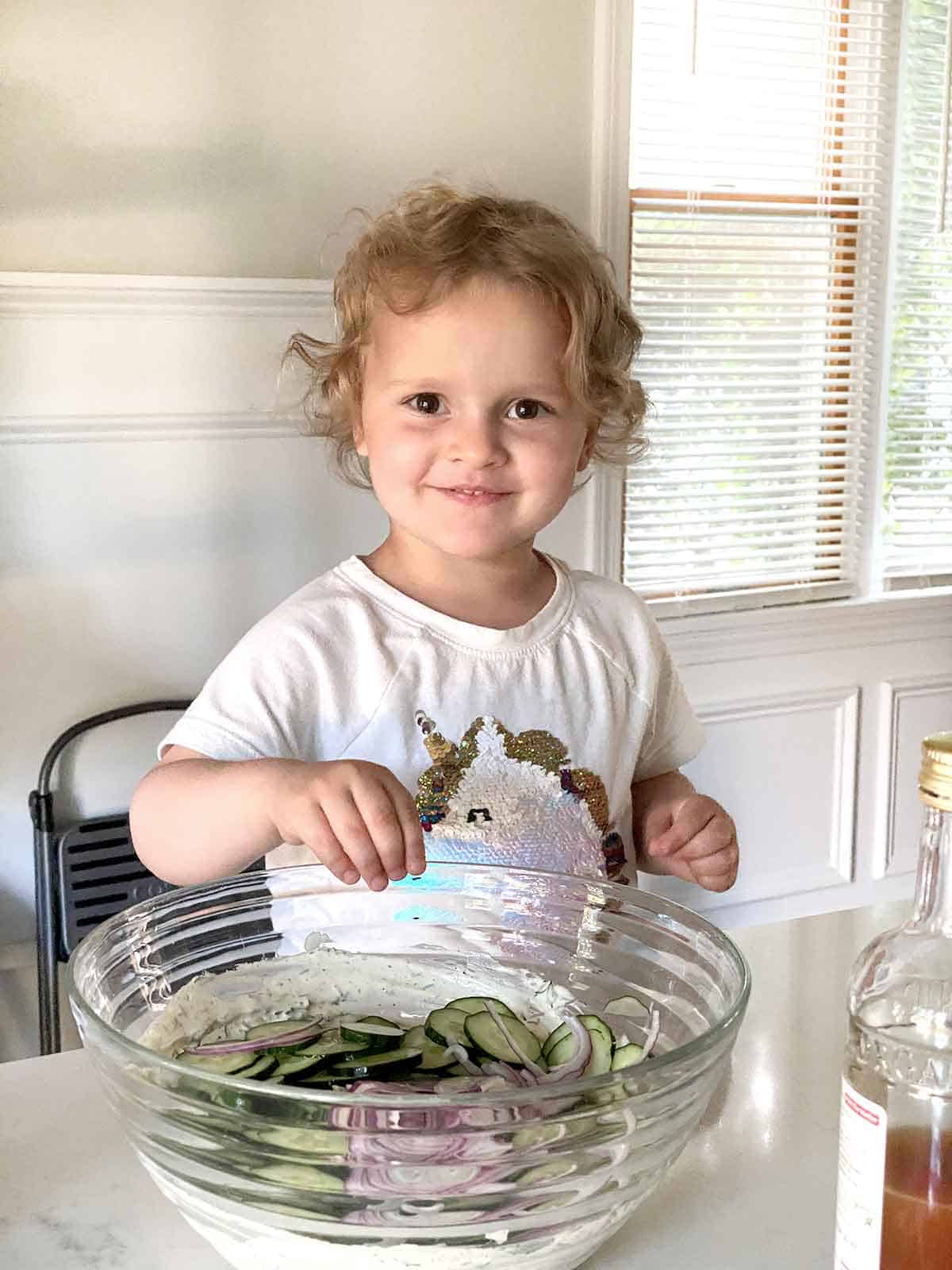 Three year old child helping make salad.