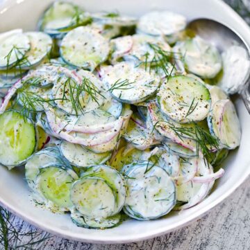 Square photo of creamy cucumber salad with yogurt and dill dressing.