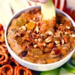 Square photo of an apple slice dipped in peanut butter dip.