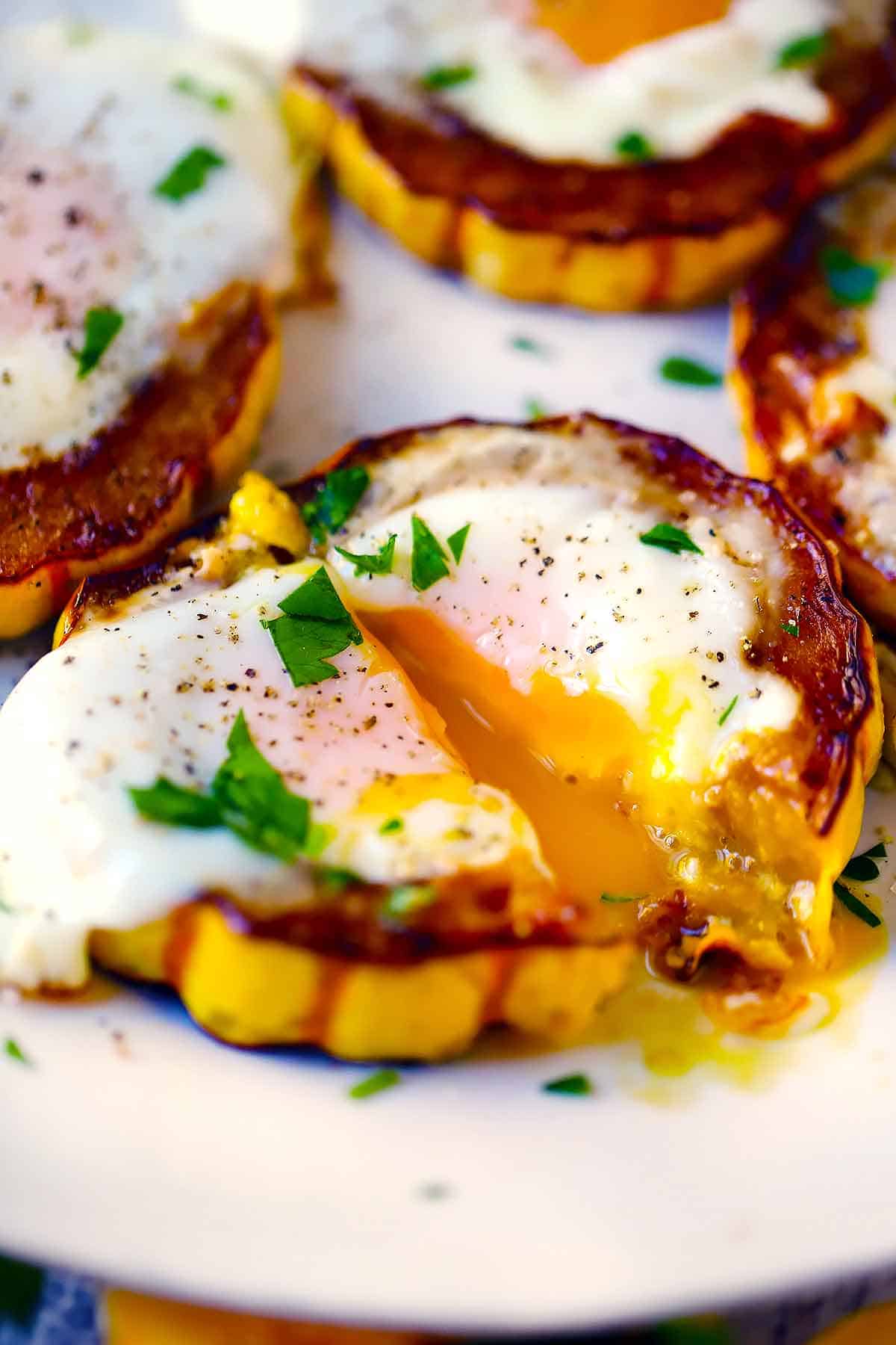 Close up photo of a fried egg with a runny yolk in a delicata squash ring.