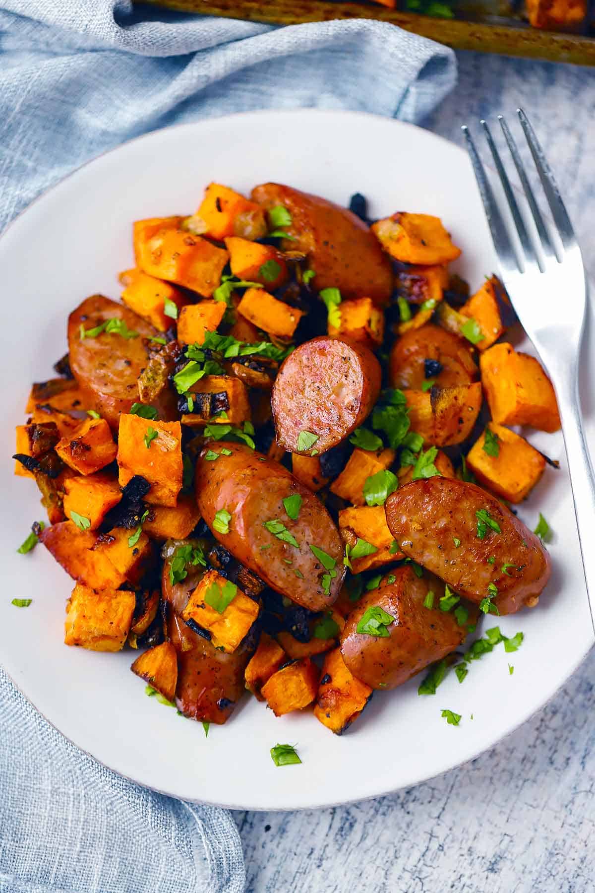 Sausage and sweet potatoes on a white plate.
