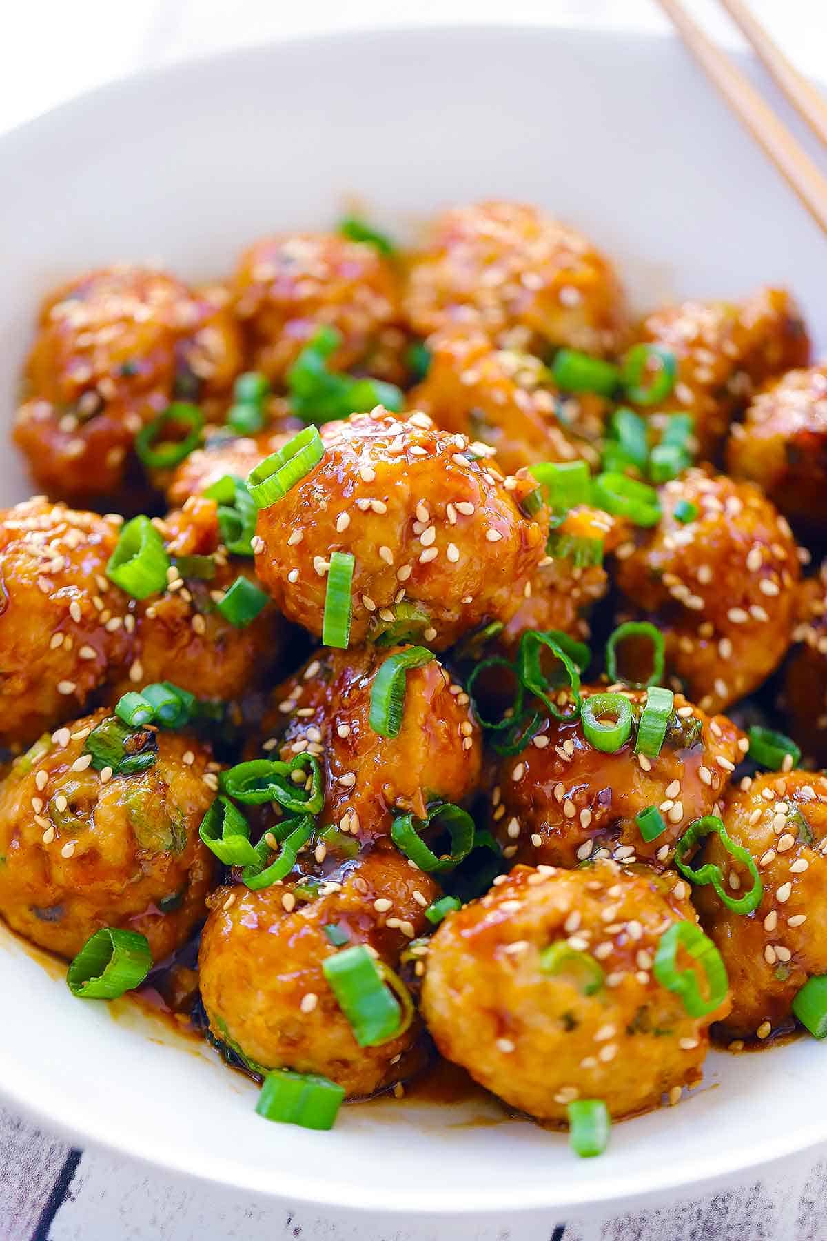 Close up photo of Asian chicken meatballs covered in soy sesame sauce.